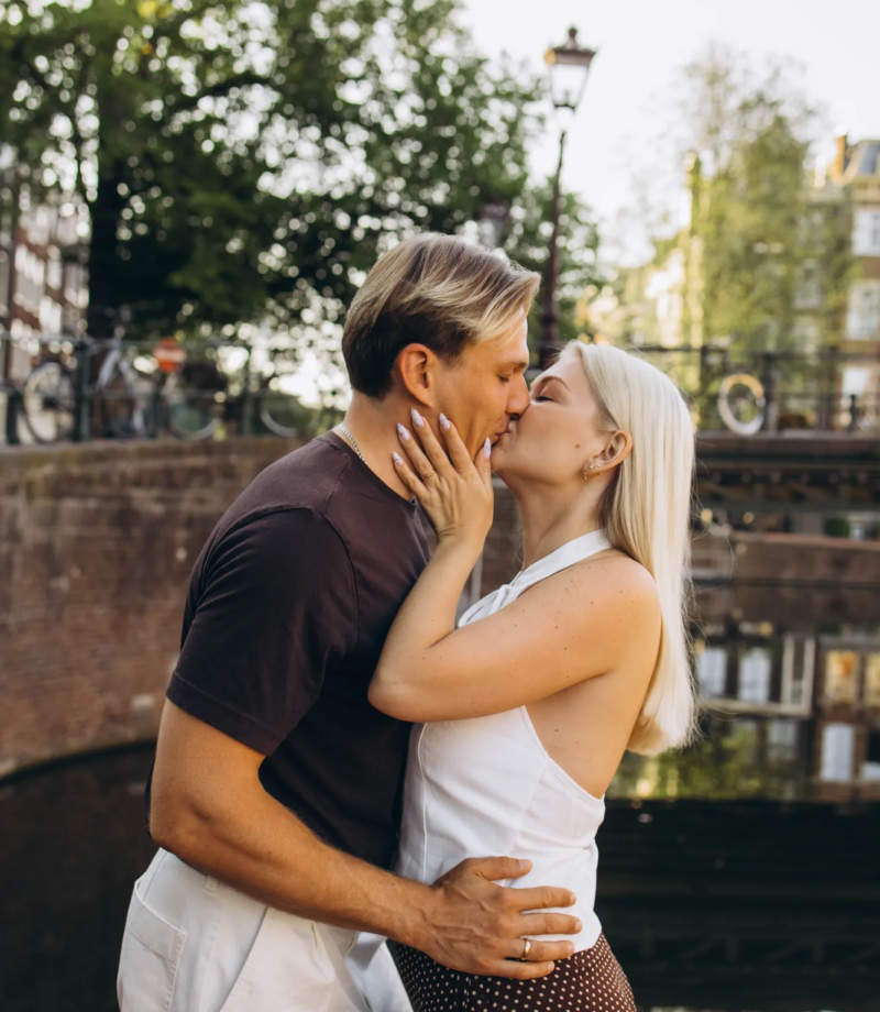 Couple kissing on a canal pontoon, canal houses reflected in the water, Amsterdam