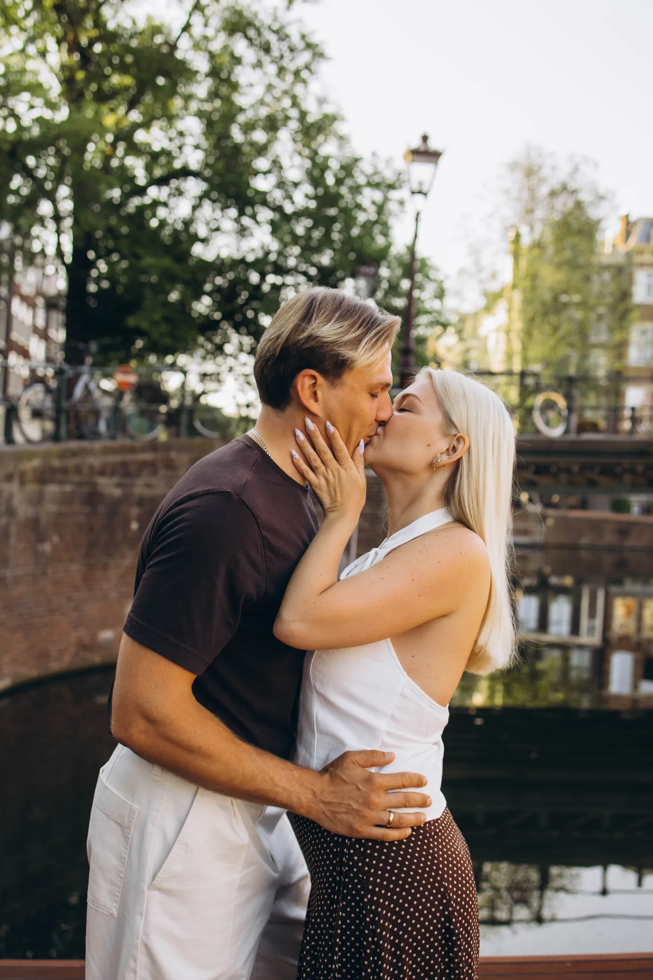 Couple kissing on a canal pontoon, canal houses reflected in the water, Amsterdam