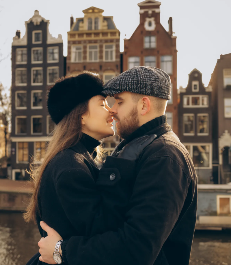 Couple kissing with a row of gabled houses across the water behind them, Amsterdam