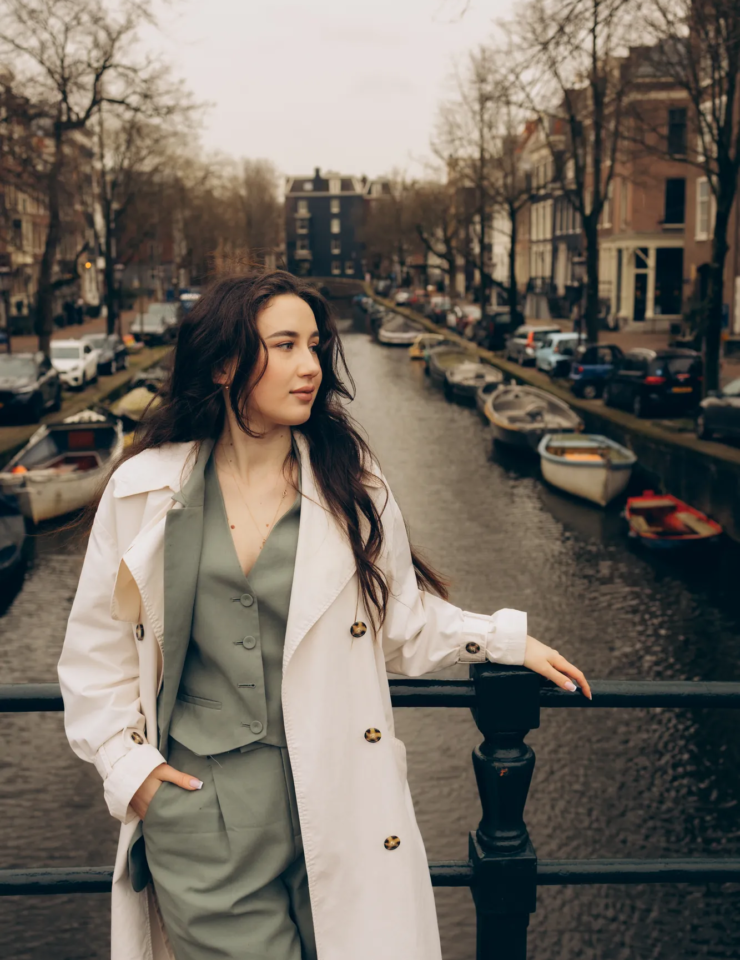 Woman in a white coat on a bridge above a canal full of small boats, Amsterdam