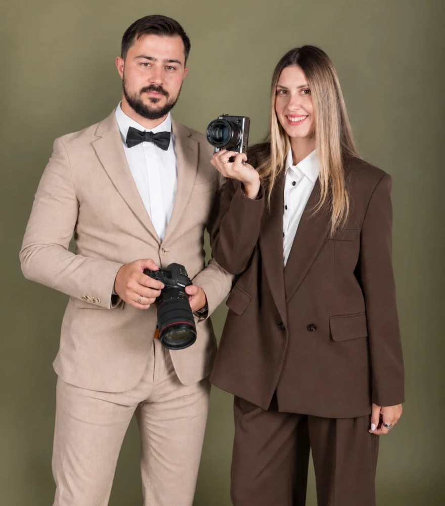 Anatolii and Julia, the husband-and-wife photographers behind Tripotographer, holding their cameras in the studio