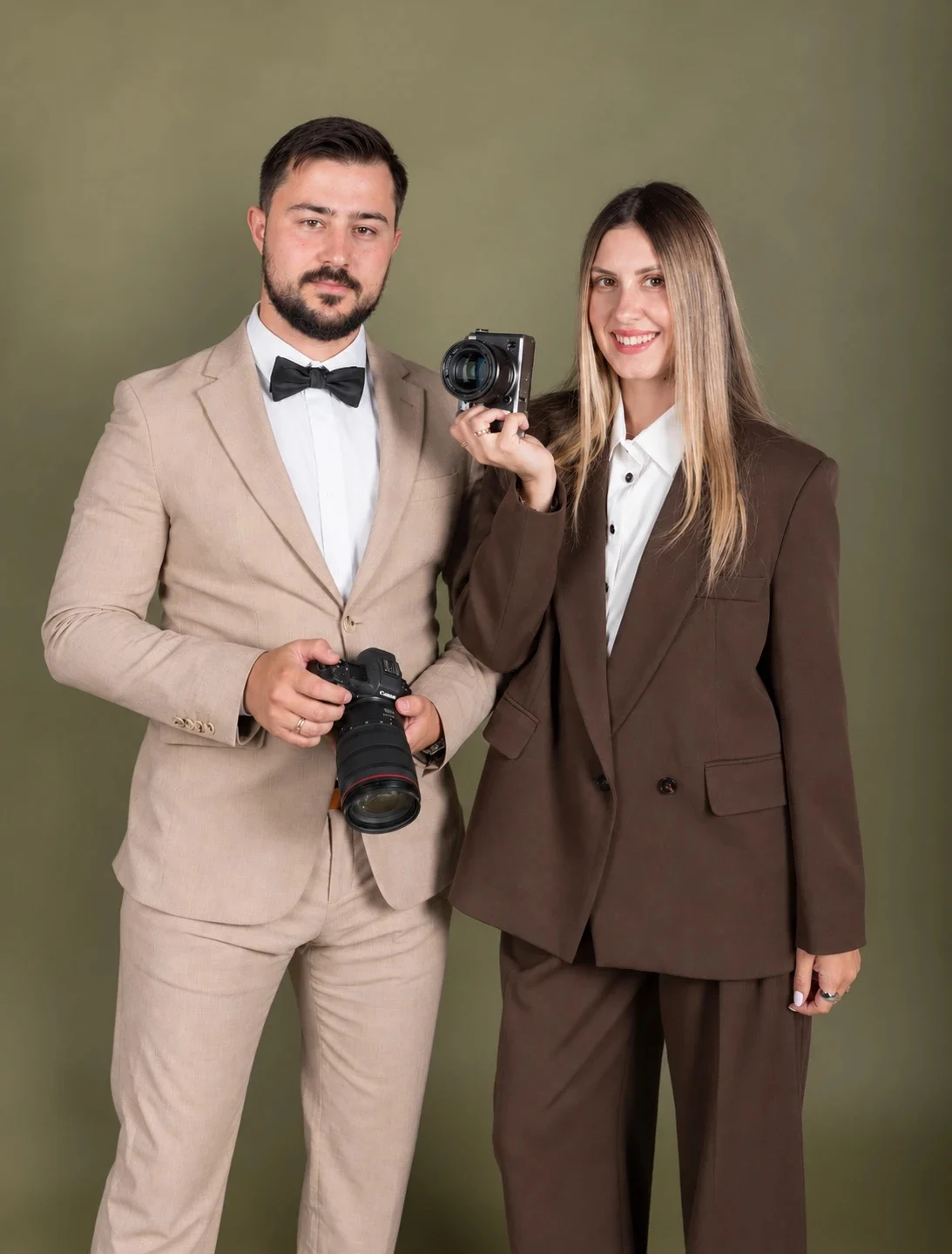 Anatolii and Julia, the husband-and-wife photographers behind Tripotographer, holding their cameras in the studio
