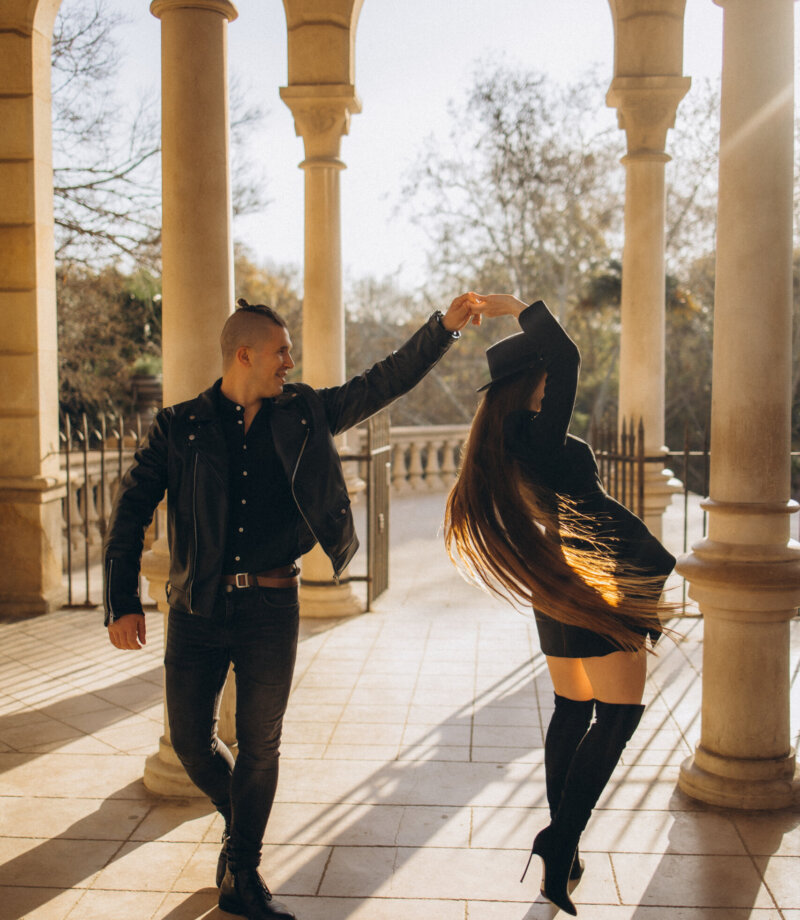Couple dancing between sunlit stone columns of the Cascada arcade in Ciutadella Park, Barcelona