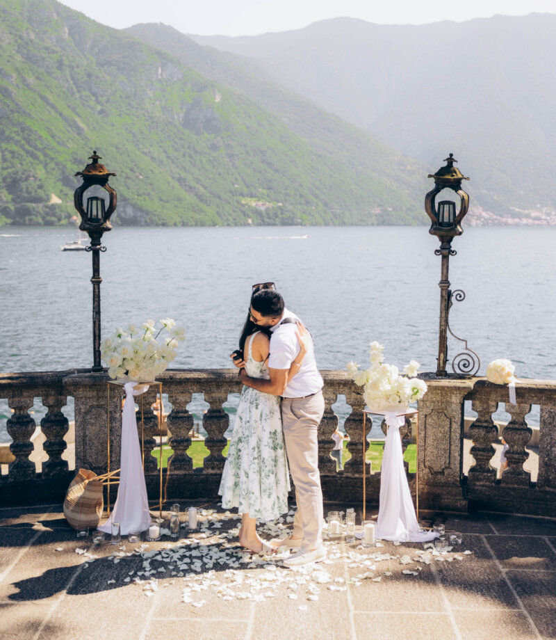 Newly engaged couple hugging on the petal-strewn terrace in Tremezzo, Lake Como