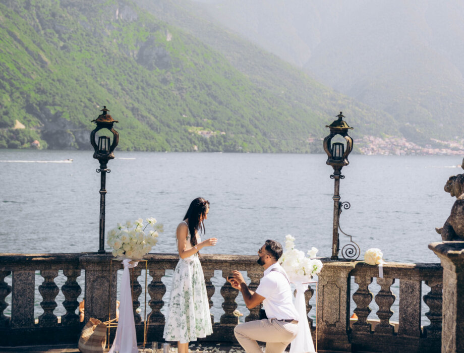 Man kneeling to propose on a petal-strewn terrace between lanterns above Lake Como in Tremezzo