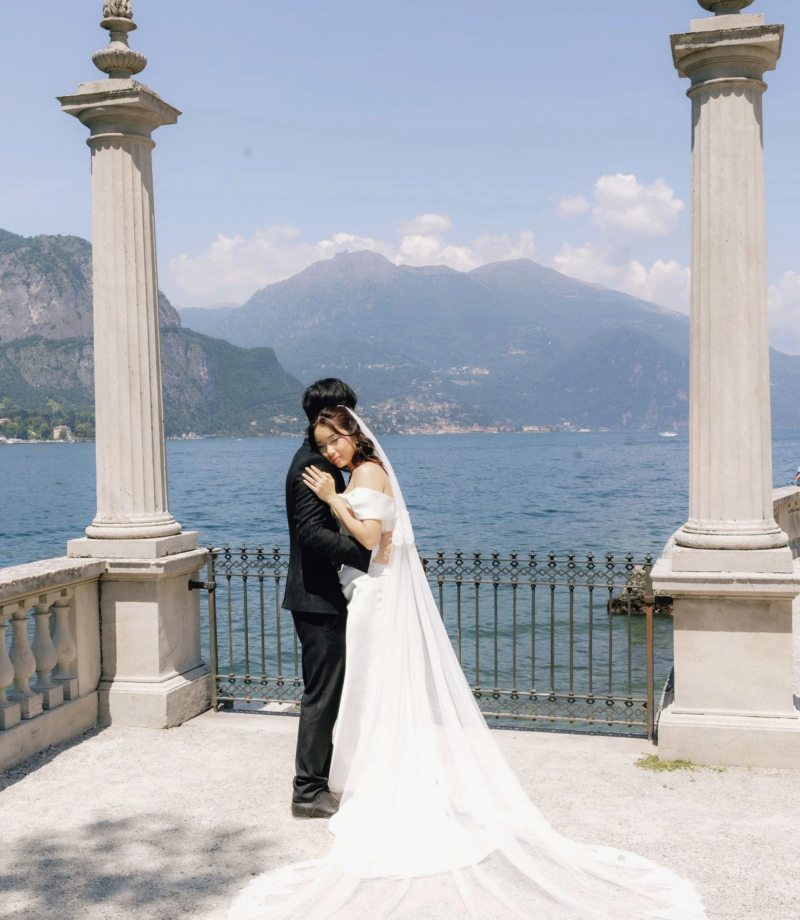 Couple between two stone columns above Lake Como with mountains behind