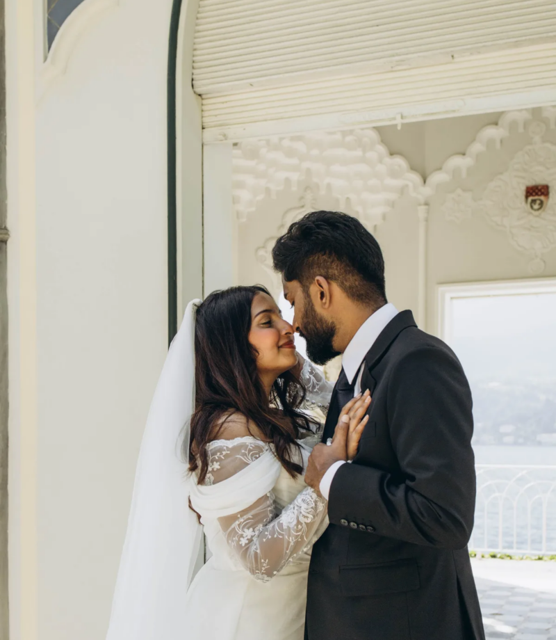 Bride and groom touching noses against the carved white archway of the Moorish pavilion at Villa Melzi, Lake Como