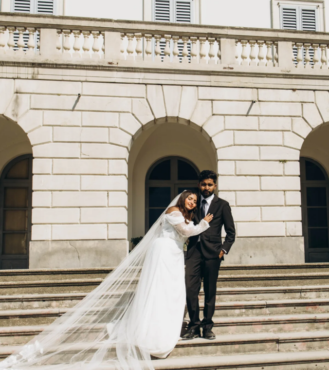Bride and groom on the wide stone steps of the white Villa Melzi facade, Lake Como