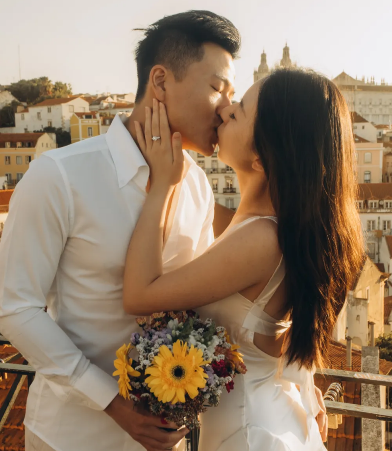 Couple with a sunflower bouquet kissing at a viewpoint at sunrise, Lisbon