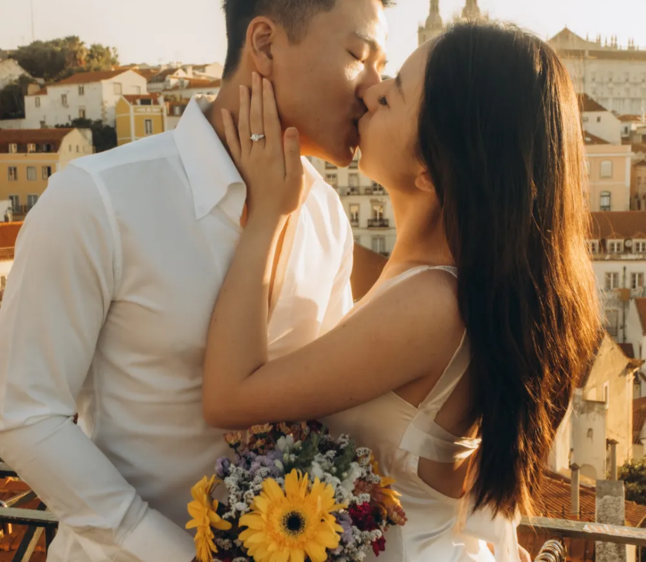Couple with a sunflower bouquet kissing at a viewpoint at sunrise, Lisbon