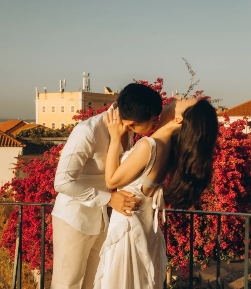 Couple with a bouquet among red bougainvillea above the river, Lisbon