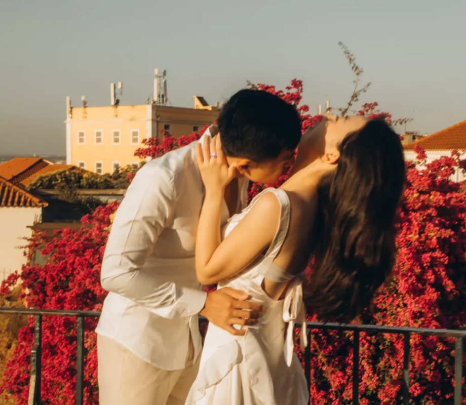 Couple with a bouquet among red bougainvillea above the river, Lisbon