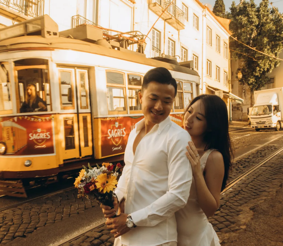 Couple with a bouquet beside a tram on a golden-lit Alfama street, Lisbon