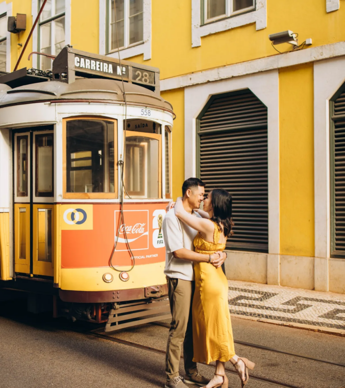 Couple embracing beside a yellow tram in Baixa, Lisbon