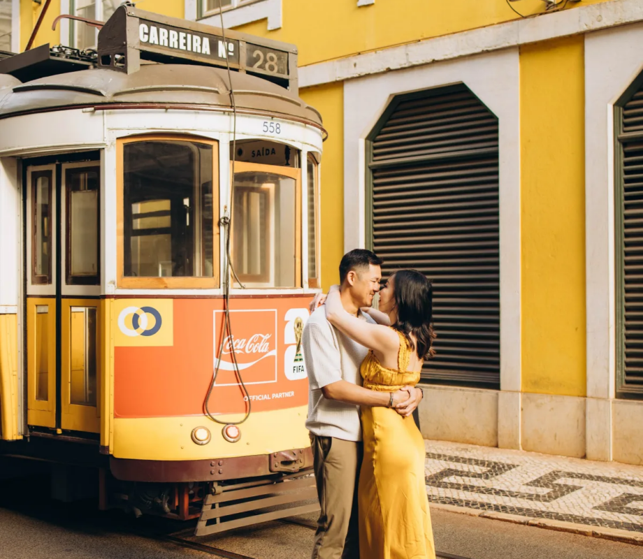 Couple embracing beside a yellow tram in Baixa, Lisbon
