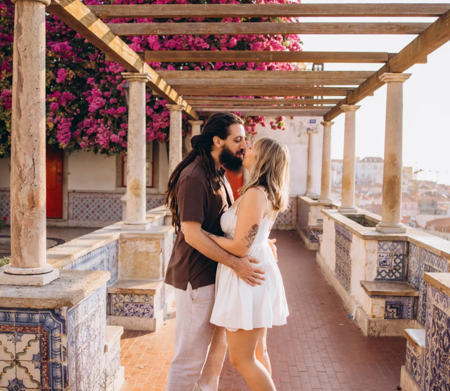 Couple kissing under the pink bougainvillea pergola at Miradouro de Santa Luzia, Lisbon