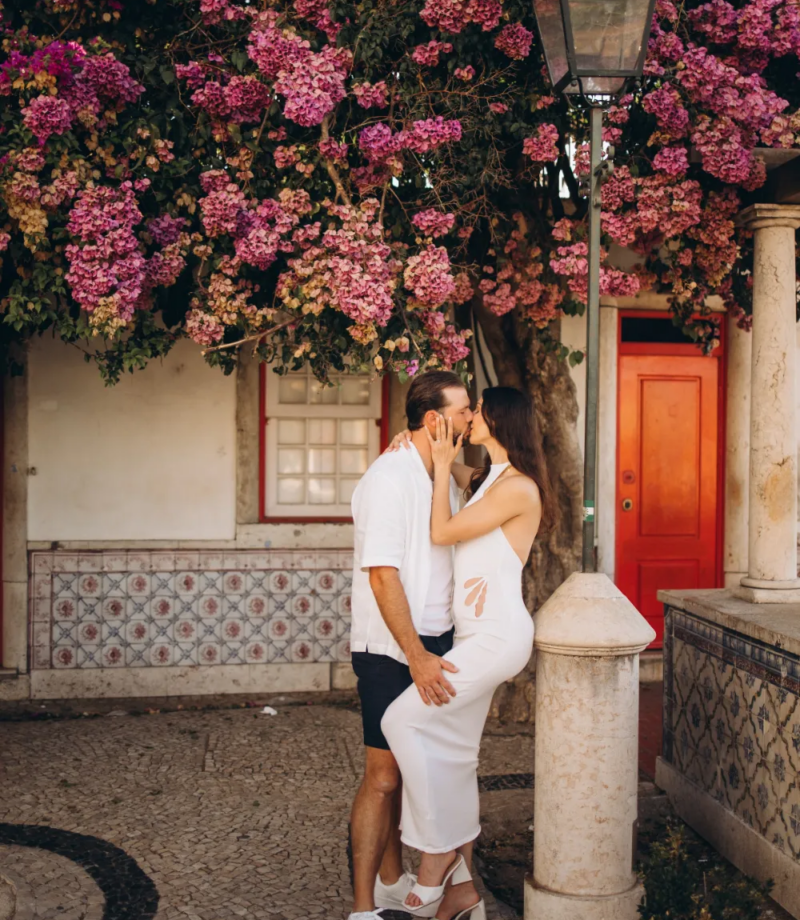 Couple by a red door under bougainvillea in Alfama, Lisbon