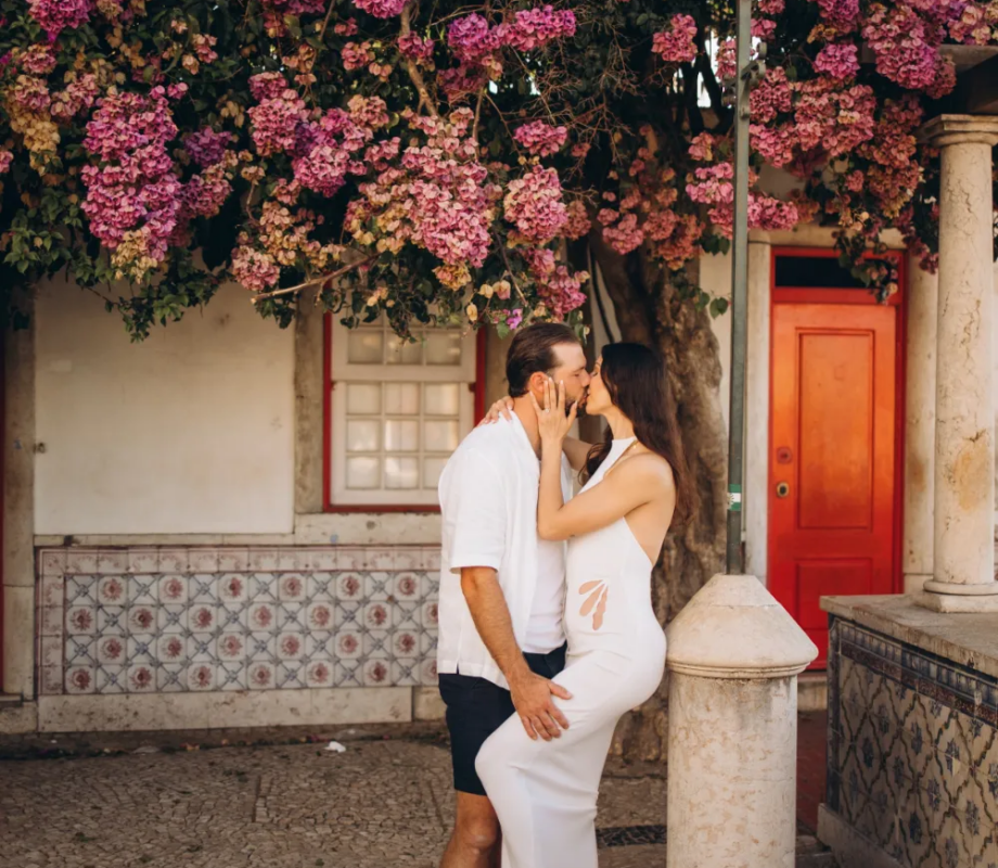 Couple by a red door under bougainvillea in Alfama, Lisbon