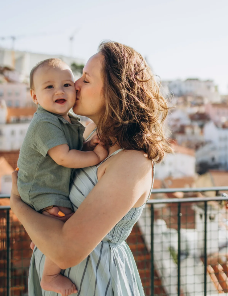 Mother kissing her baby at an Alfama viewpoint above the rooftops, Lisbon