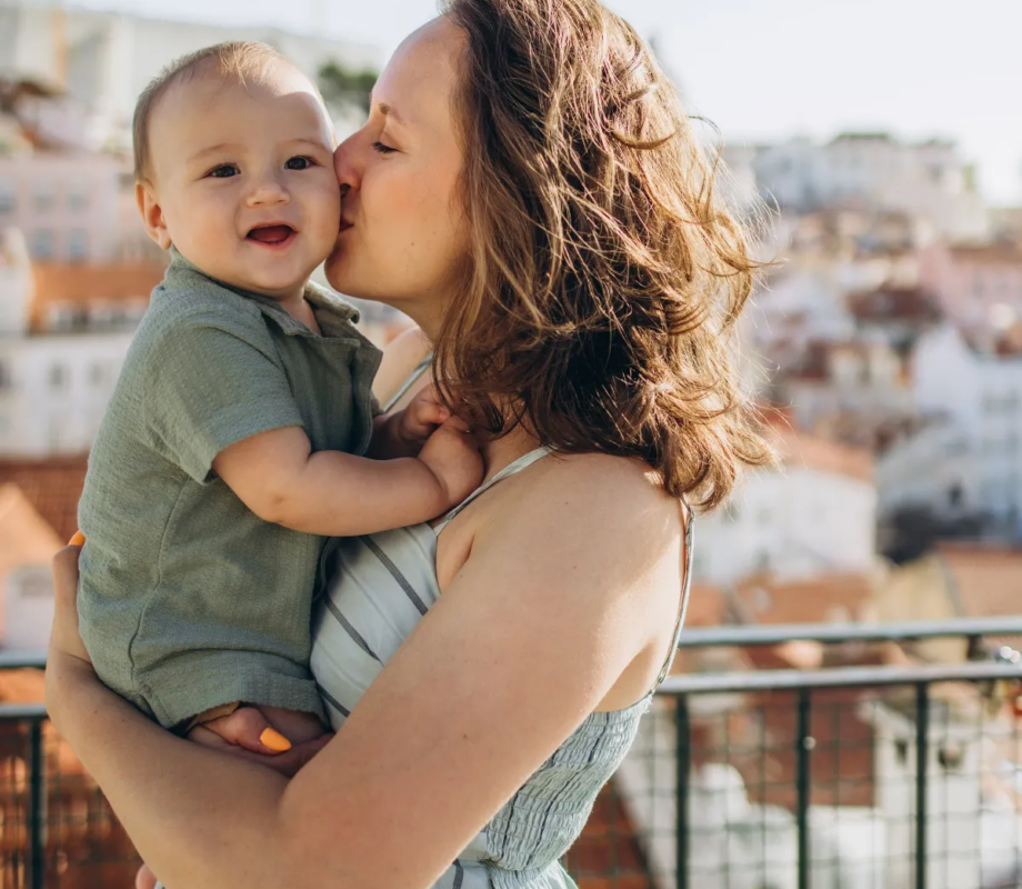 Mother kissing her baby at an Alfama viewpoint above the rooftops, Lisbon