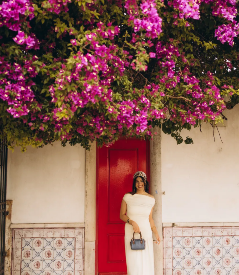 Woman by a red door under a cascade of bougainvillea, Lisbon