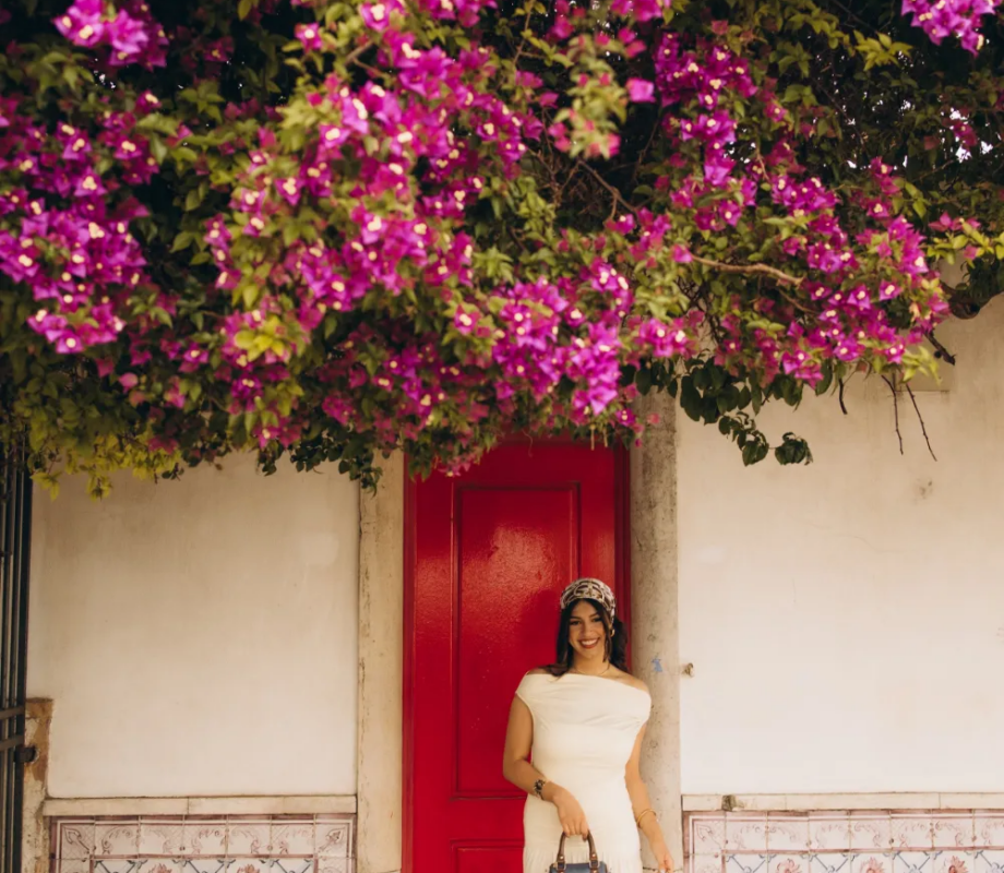 Woman by a red door under a cascade of bougainvillea, Lisbon