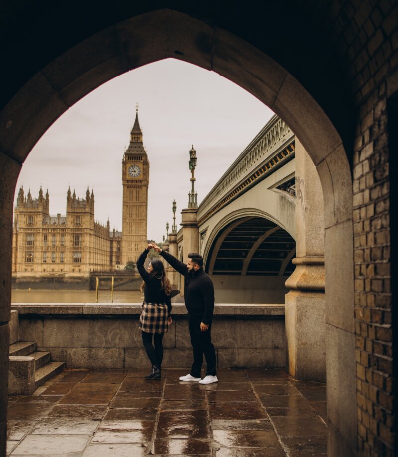 Couple dancing in the stone arch under Westminster Bridge, Big Ben framed behind, London