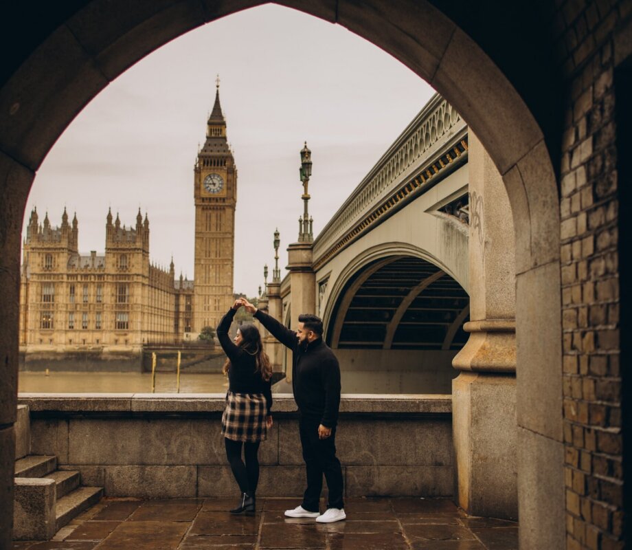 Couple dancing in the stone arch under Westminster Bridge, Big Ben framed behind, London