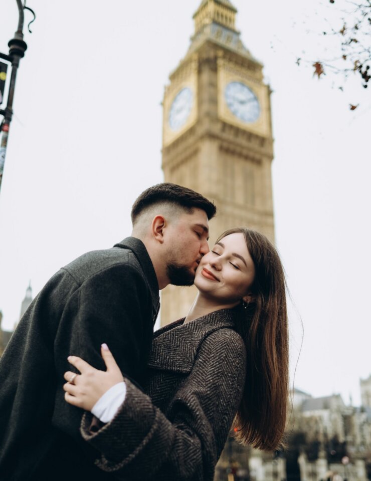 Man kissing his partner's cheek beneath the Elizabeth Tower, London