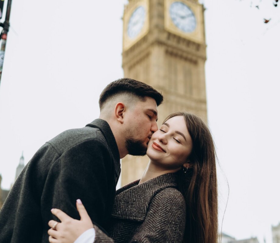 Man kissing his partner's cheek beneath the Elizabeth Tower, London