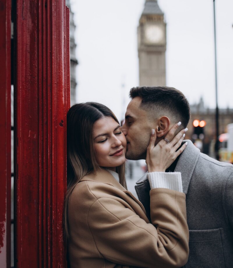 Couple kissing inside a red telephone box with Big Ben behind, London