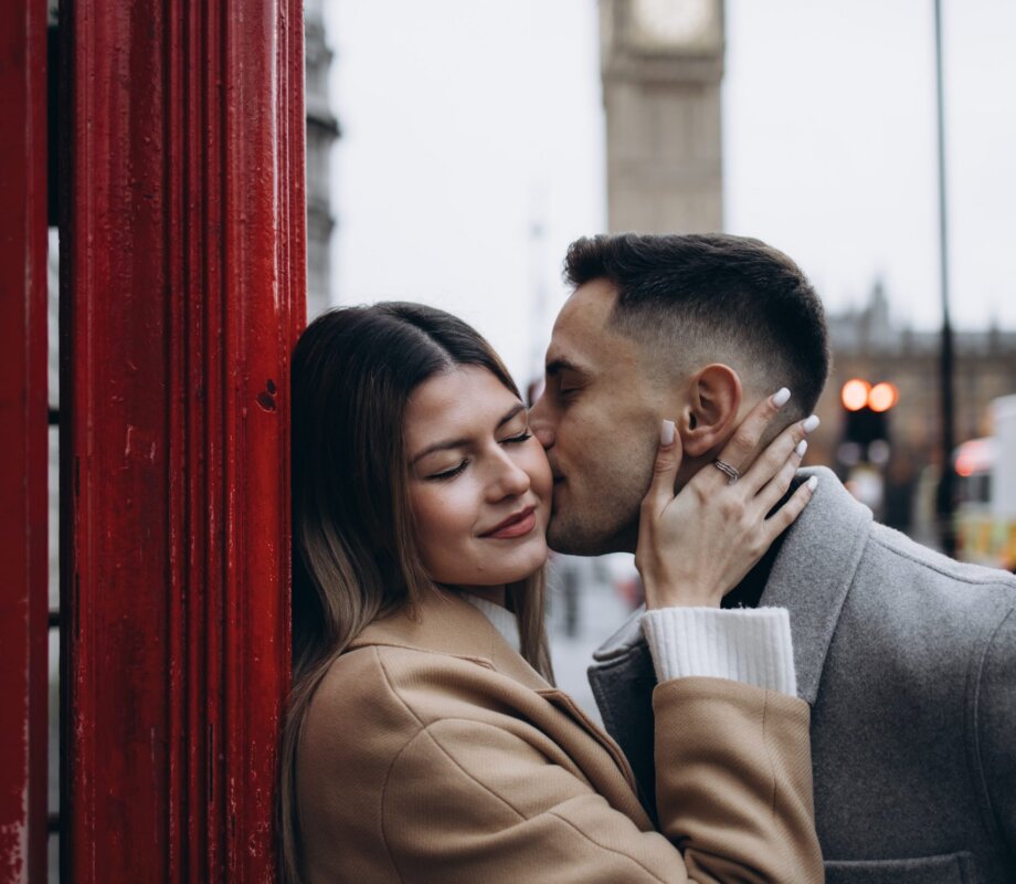 Couple kissing inside a red telephone box with Big Ben behind, London