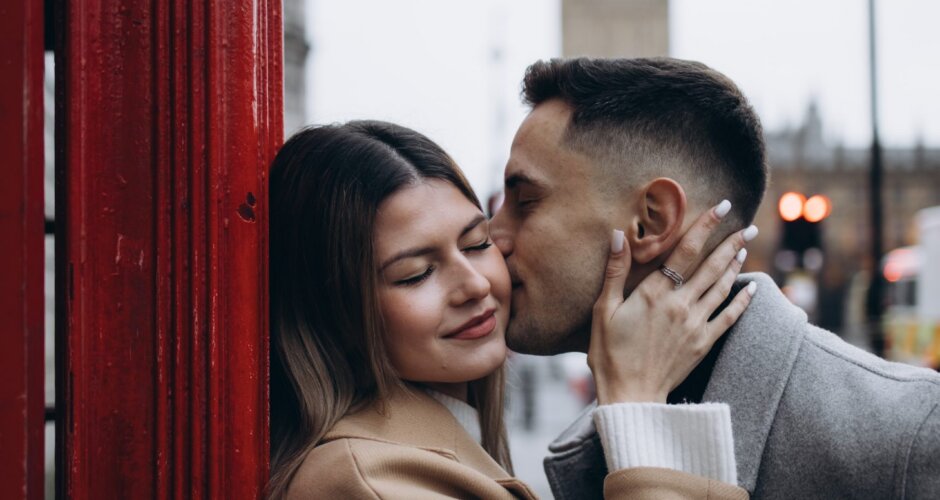 Couple kissing inside a red telephone box with Big Ben behind, London