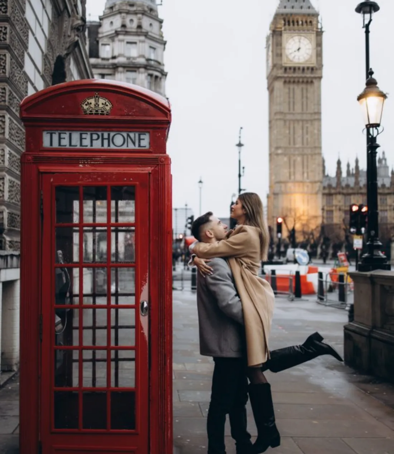 Couple kissing beside a red telephone box near Parliament Square, Big Ben behind, London