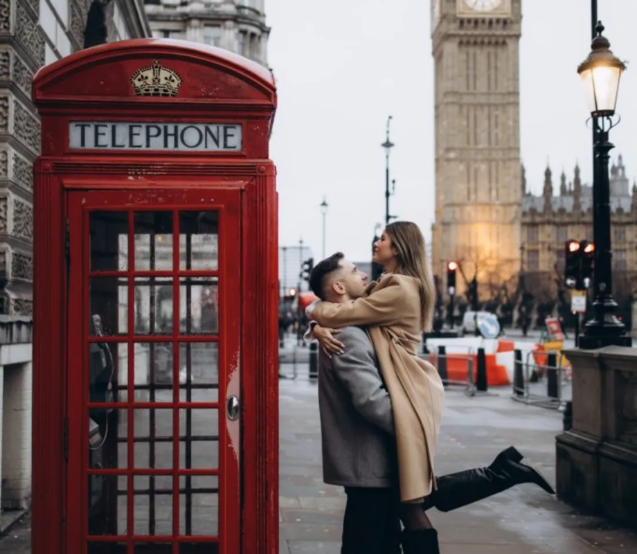 Couple kissing beside a red telephone box near Parliament Square, Big Ben behind, London