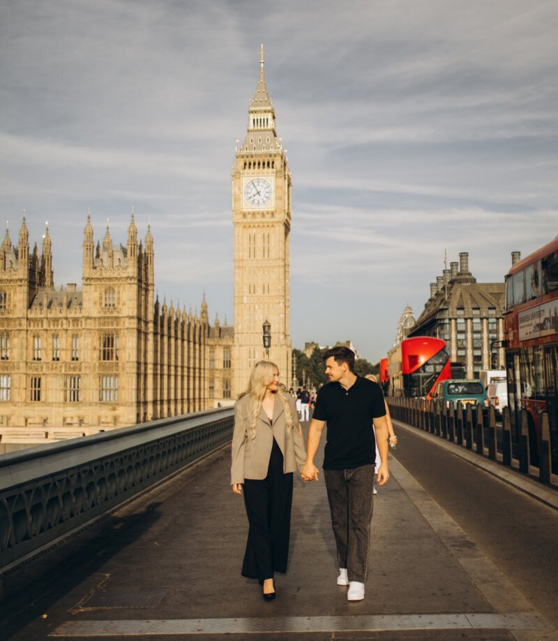 Couple walking hand in hand across Westminster Bridge towards Big Ben, London