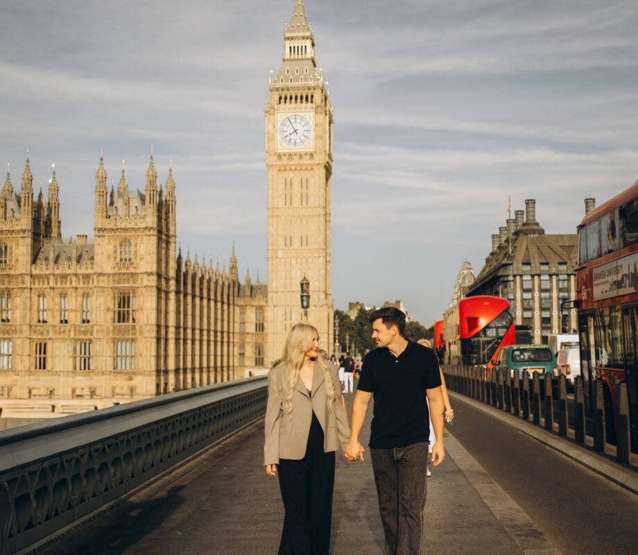 Couple walking hand in hand across Westminster Bridge towards Big Ben, London