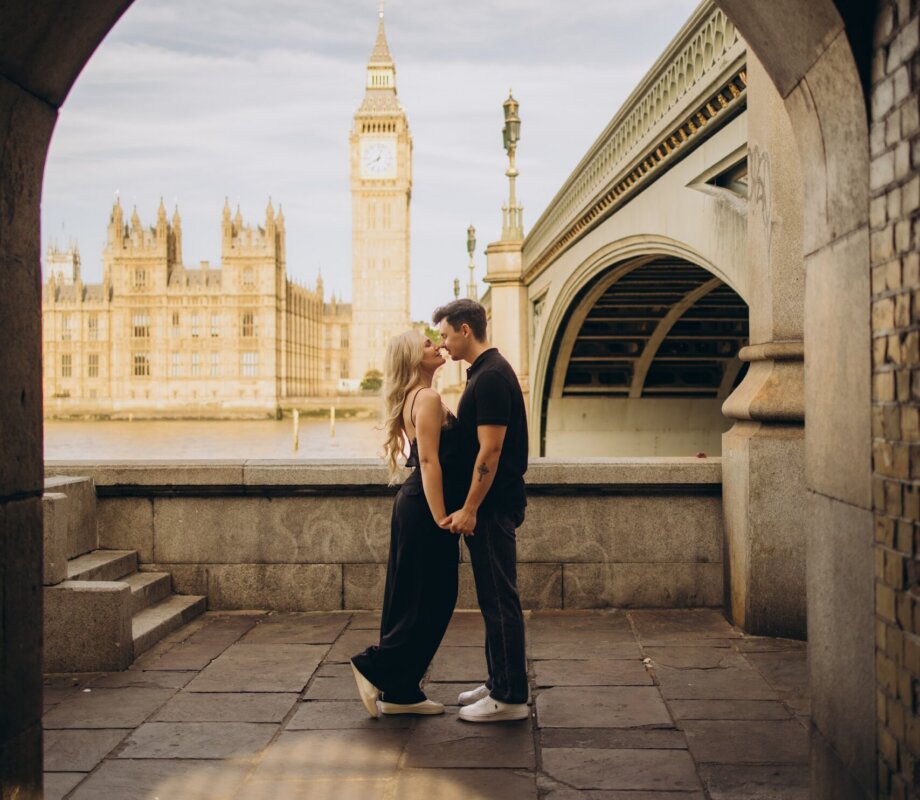 Couple kissing in the stone arch under Westminster Bridge, Big Ben framed behind, London