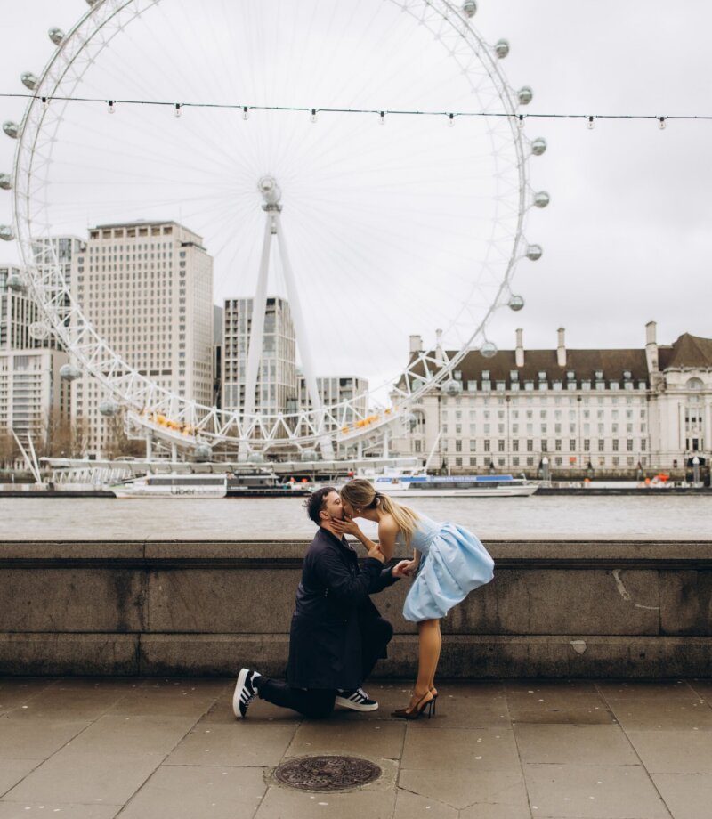 Couple kissing after the proposal on the Victoria Embankment, London Eye across the Thames