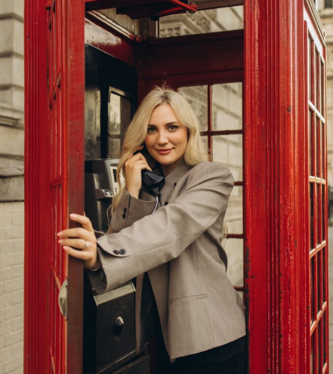 Woman laughing on the phone inside a red telephone box, London