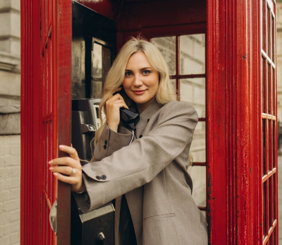 Woman laughing on the phone inside a red telephone box, London