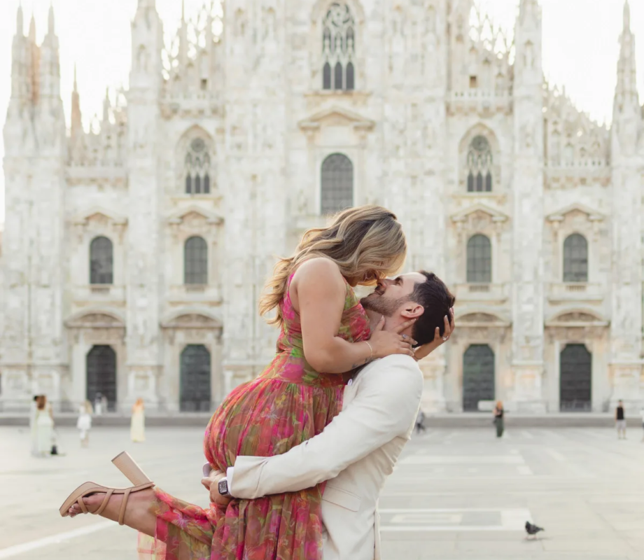 Man lifting his partner for a kiss on Piazza del Duomo, the cathedral behind, Milan