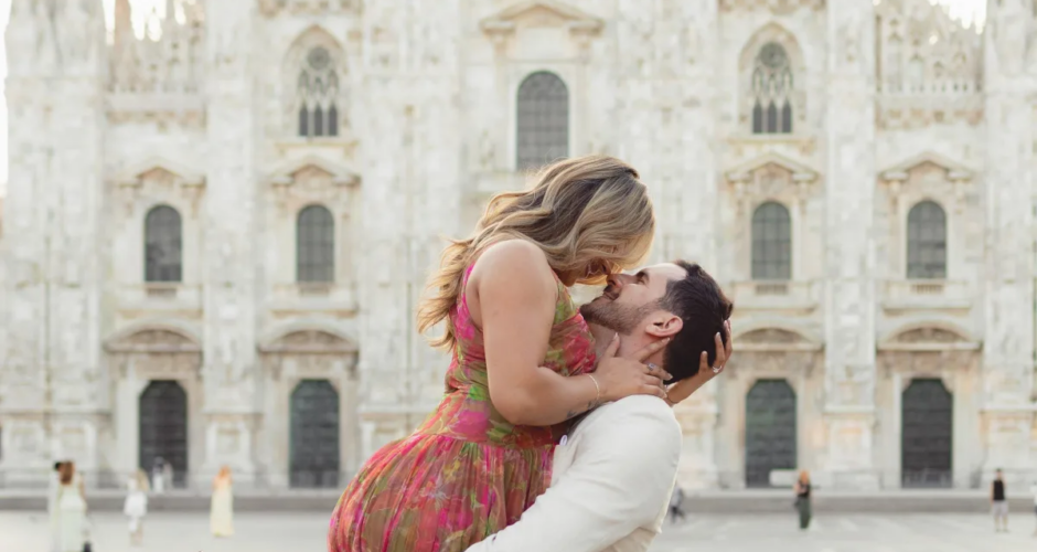 Man lifting his partner for a kiss on Piazza del Duomo, the cathedral behind, Milan