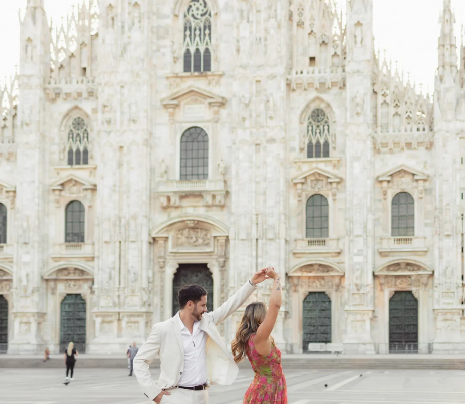 Man spinning his partner by the hand on the open Piazza del Duomo, the gothic cathedral facade behind, Milan