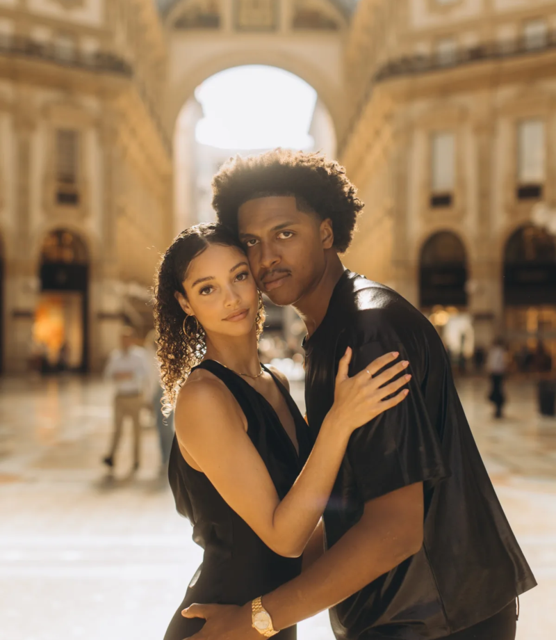 Couple in black standing close under the glass vault of the Galleria Vittorio Emanuele II, Milan