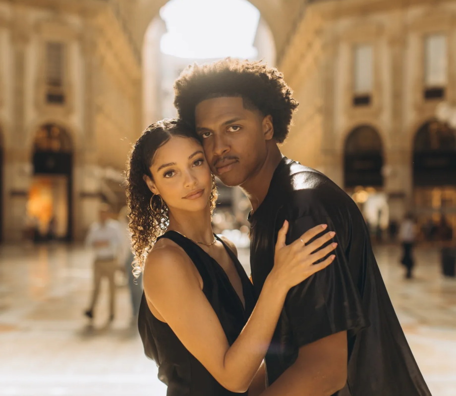 Couple in black standing close under the glass vault of the Galleria Vittorio Emanuele II, Milan
