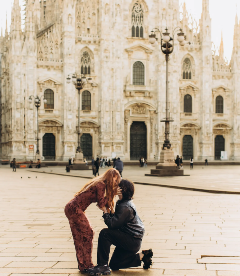 She hugs him as he kneels to propose on an empty Piazza del Duomo, Milan
