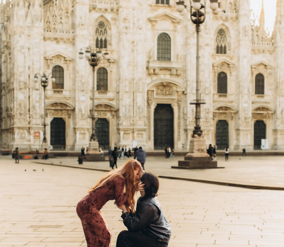 She hugs him as he kneels to propose on an empty Piazza del Duomo, Milan