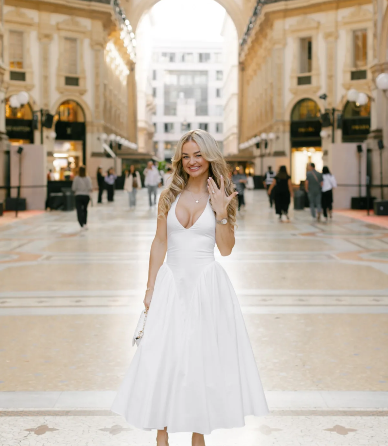 Woman in a white dress showing her ring under the great arch of the Galleria, Milan