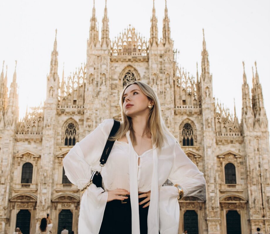 Woman in a white blouse glancing up toward the spires of Milan Cathedral, Milan